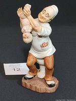 Full view of vintage porcelain doctor figurine holding newborn baby upside down