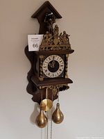 Front view of vintage Dutch wall clock showing detailed brass work, clock face, weights and pendulum.
