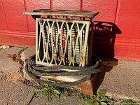 Front view of the turnover toaster showing decorative metal patterned housing and cord coiled around the base, placed outdoors against a red surface.