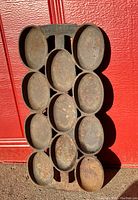 Full view of antique cast iron mold showing 12 oval indentations for baking cookies or biscuits.