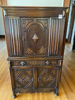 Front view of the antique wooden dining room cabinet showing carved doors and drawer details.
