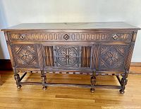 Full front view of the antique wooden sideboard showing all carved details and leg supports.