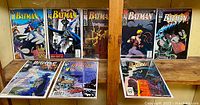 Eight comics displayed on shelf: four Batman issues on top row and three Detective Comics plus one annual on bottom row