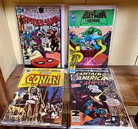 Four French language black and white comic book reprints from Edition Heritages showing Spider-Man, Batman and Robin, Captain America and Falcon, and Conan titles, each bagged and boarded.