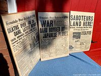 Three vintage Honolulu Star-Bulletin WWII newspaper front pages displayed standing, showing headlines about Japanese attacks on Oahu and wartime news.
