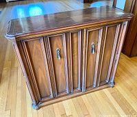 Front view of the vintage wood cabinet showing the two paneled doors with keyholes and the overall rectangular shape.
