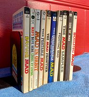 Photo showing side view of 10 vintage Mad Magazine paperbacks lined up, titles clearly visible on spines.