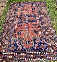 Full view of the carpet laid out on grass showing the overall design and condition.