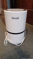 Front view of white Levoit LV-H132 air purifier with black trim and power cord visible on floor.