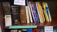 Shelf of assorted homeopathy and herbal medicine books including large reference volumes and smaller guides.