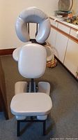Front view of the grey massage chair showing U-shaped headrest, chest cushion, armrests, seat seat, and knee supports.