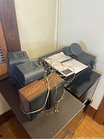 Photo showing two Realistic speakers with wood grain finish and RCA stereo receiver along with cables and Optimus amplifier on black surface.