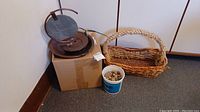 Photo of copper tabletop fountain and wicker basket with a bucket of stones near them.