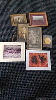 Full view of all seven photos on floor, showing four framed (one broken frame) and three unframed photos laid out