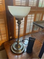Front view of one antique brass-colored floor lamp with white glass bowl shade next to a small heater, showing full height and design details.