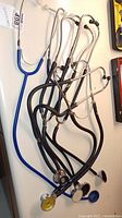 Full view of four stethoscopes with black and blue tubing, showing earpieces and chest pieces.