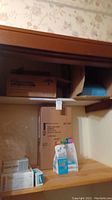 Photo showing shelf with unopened boxes including table paper, pillow cases, and blue disposable underpads