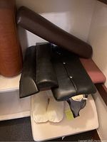 Six chiropractic therapy wedges of various shapes and colors stacked on shelves including rectangular, contoured, cylindrical bolsters in brown and black materials.