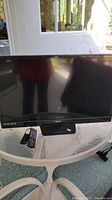 Front view of the Sanyo 32-inch LED television on a table with two remote controls in front.
