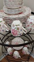 Stacked plates and cups showing floral Rose Chintz pattern inverted on a metal shelf