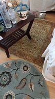 Rectangular floral patterned runner rug under coffee table and part of round floral rug next to couch