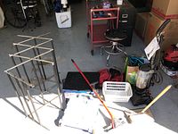 Photo showing vacuum, clothes drying racks, duffle bag, basket, dustpan, and crate in garage.