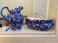 Blue and white floral ceramic pitcher and tureen side by side on shelf