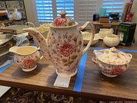 Full view of the Rose Chintz tea set showing teapot, sugar bowl, and creamer on wooden table.