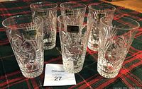Seven clear hand-cut lead crystal drinking glasses in the Lausitzer Pinwheel Star pattern shown arranged on a plaid fabric, with original stickers on most glasses.