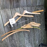 Wooden clothes hangers of various sizes and styles, including a branded wooden hanger.