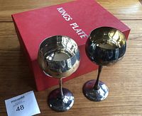 Two silver-plate wine goblets standing upright next to their original red Kings Plate box on a wood surface.
