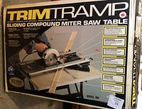 Front of the packaging showing brand Trim Tramp and model 101 with detailed features of the sliding compound miter saw table, designed for converting circular saws to miter saws.