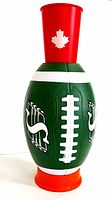 Football-shaped cup holder showing red top cup holder with white maple leaf and orange base, green football textured body with white laces and logos