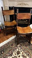 Front view of both chairs showing leather seats and backs with brass studs