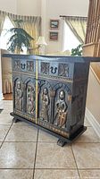 Front view with carved medieval figures and toolbox tape measure for scale