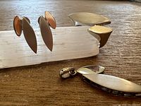 Ring, pendant, and pair of drop earrings displayed on wooden surface with selenite holder