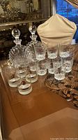 Photo showing a pair of Villeroy & Boch Platano crystal decanters with spherical stoppers and multiple Buffalo Trace collectible whiskey glasses arrayed on a table.