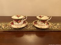Two Royal Albert Old Country Roses teacups on matching saucers seen from the front showing floral pattern and gold trim.