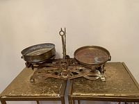 Front view of Victorian antique balance scale showing ornate cast iron base and brass pans