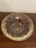 Large clear glass bowl with silver overlay floral and scroll designs on rim, showing footed base with four supports