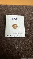 Front view of the vintage Rotary International 10K gold pin on white card showing emblem and markings.