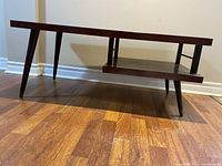 Side view of the mid century modern coffee table showing the angled legs and lower shelf