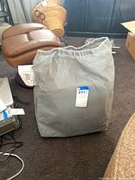Gray folded Duckcovers Defender Series double SUV car cover with visible textured pattern, shown standing on carpeted floor with a label tag.