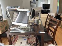 Photo of wood dining table with computer and office accessories on top, showing table finish and structure.