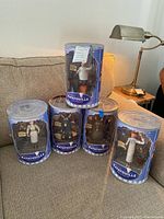 Five Disney Pixar Ratatouille collectible figures in original blue packaging on sofa, varying poses visible.