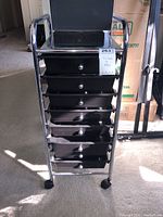Frontal view of the file rack showing the metal frame, six plastic bins with knobs, and caster wheels.
