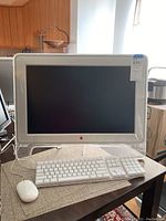 Front view of the Apple iMac with keyboard and mouse on a table, showing the 28 inch screen and translucent design.