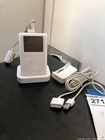 White Apple iPod inserted in one of the two white docks, power cord visible with 30-pin connector cable.