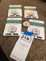 Five TrackR Bravo lost item trackers in packaging, showing two gold and three silver units, displayed on carpet.