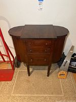 Front view of the antique table showing side compartments closed and three front drawers with round wooden knobs.